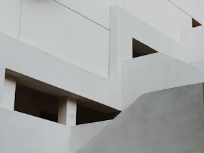 Geometric shapes and angles form a modern architectural structure, featuring rectangular openings and smooth surfaces. The design emphasizes minimalism and clean lines.