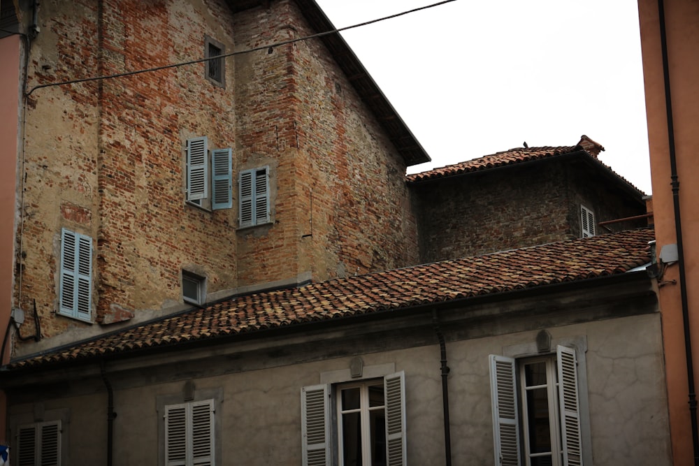Bâtiment en brique brune et grise avec fenêtres à persiennes