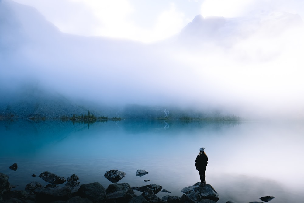 person standing on rock overlooking body of water