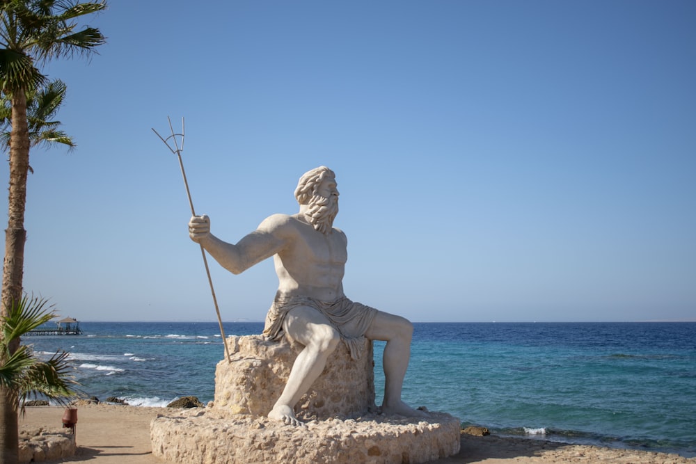 topless man statue near ocean during daytime