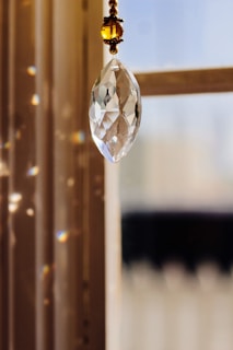 Close-up of a clear crystal prism casting soft light patterns on a beige fabric
