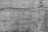 Rough textured concrete wall with visible cracks running horizontally and vertically. The surface appears weathered and aged, with various shades of gray contributing to an overall rustic and rugged look.