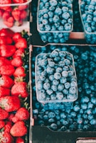 Bright red apples and deep blue blueberries neatly arranged in crates.