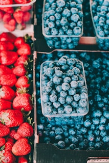 Bright red apples and deep blue blueberries neatly arranged in crates.