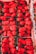 A collection of vibrant red strawberries neatly arranged in cartons. The strawberries are fresh, large, and shiny with green stems. The image highlights the variety and abundance of the fruit.