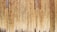 Vertical wooden planks aligned closely together create a textured pattern with varying shades of natural wood grain. The surface appears weathered, with some planks showing darker areas due to age or exposure.