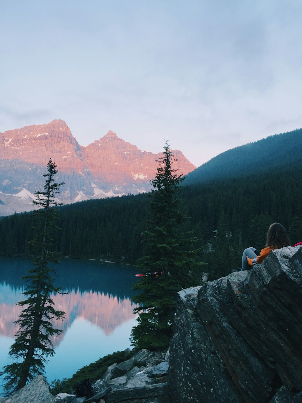 woman sits back and looks the scenery of lake and mountains