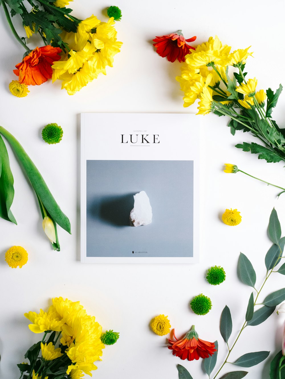 Luke book, white stone, and yellow and red flowers