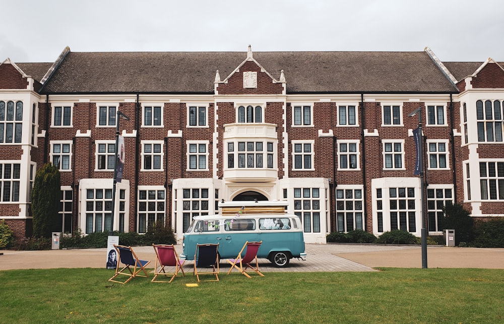 blue Volkswagen park near deck chairs in front of brown painted mansion