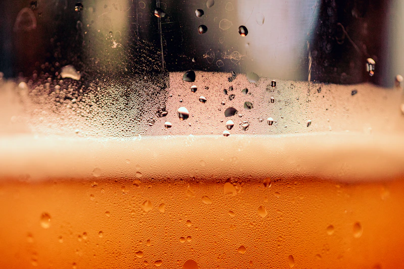 Close-up of a fresh pint of dark stout with perfect creamy foam head inside a cozy bar