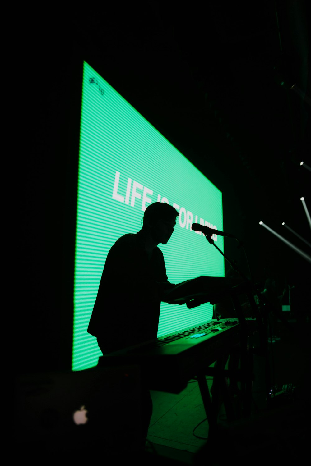 silhouette of man standing beside electric keyboard