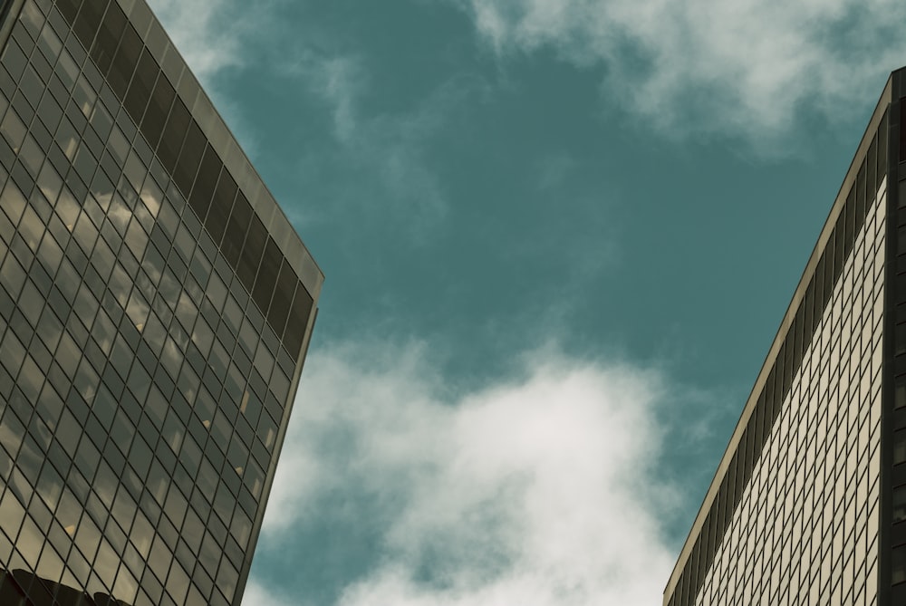 Fotografía de ángulo bajo de un edificio de vidrio gris bajo el cielo azul y blanco durante el día