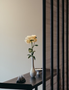 A sleek narrow-opening vase holding a single elegant stem, placed on a minimalist dining table centerpiece.