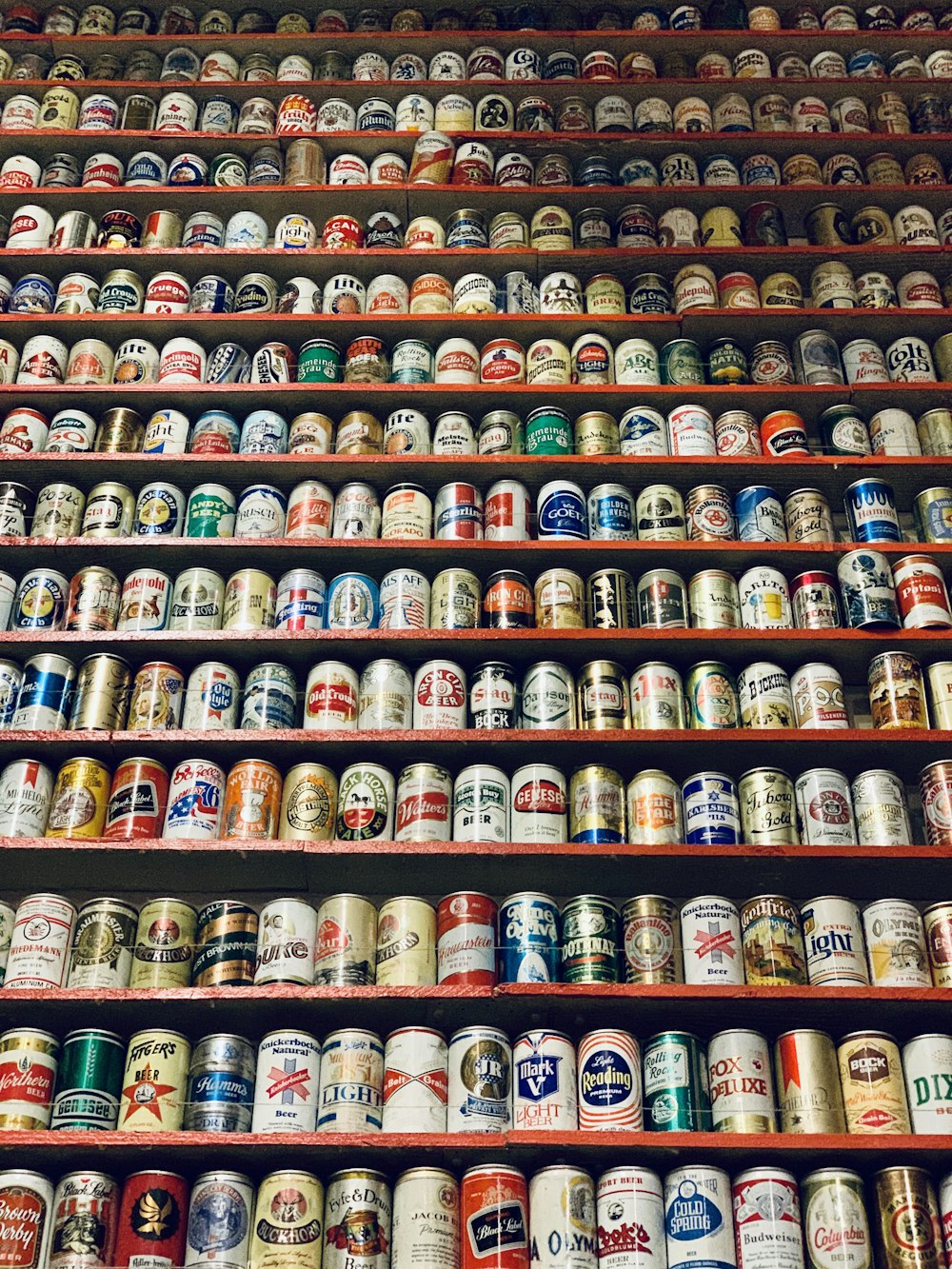 Lote de latas de bebidas de marcas variadas en el estante