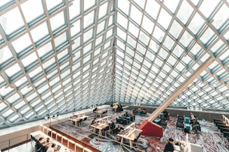 A bright, modern library interior with students sitting at spaced desks, focused on their work.