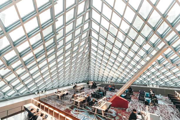 A bright, modern library interior with students sitting at spaced desks, focused on their work.
