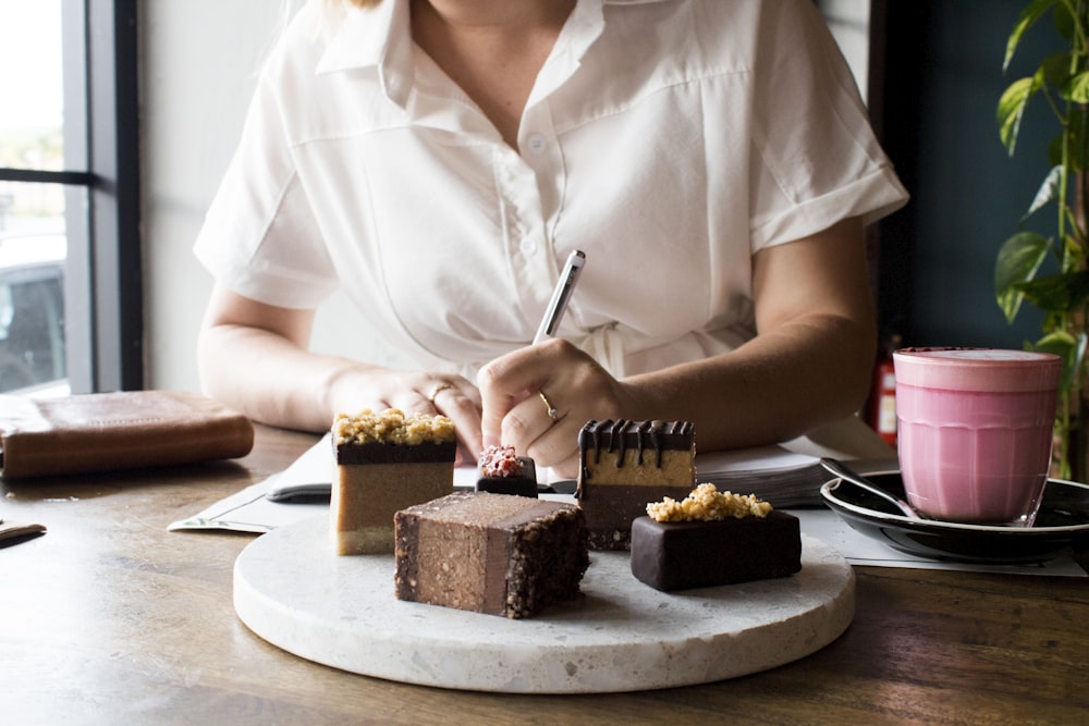 a woman sitting at a table with a plate of desserts