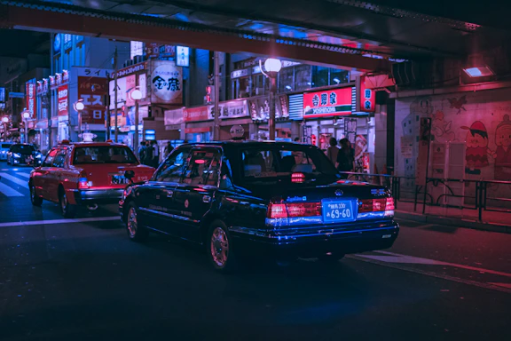 A vibrant street scene with diverse cars from Japan, America, and Europe under colorful city lights.