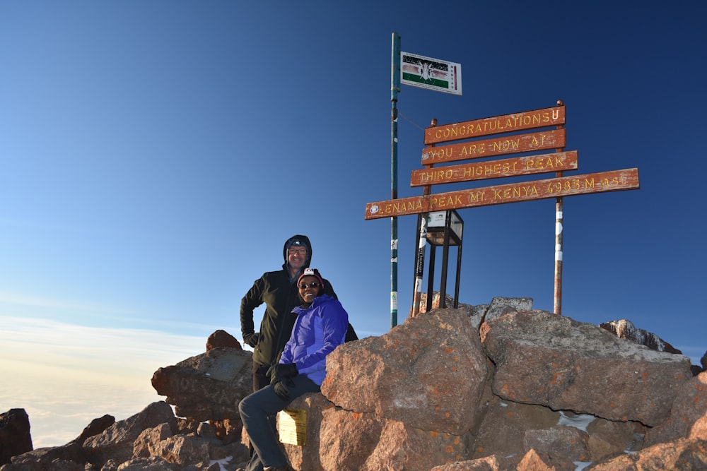 man and woman standing on mountain's peak