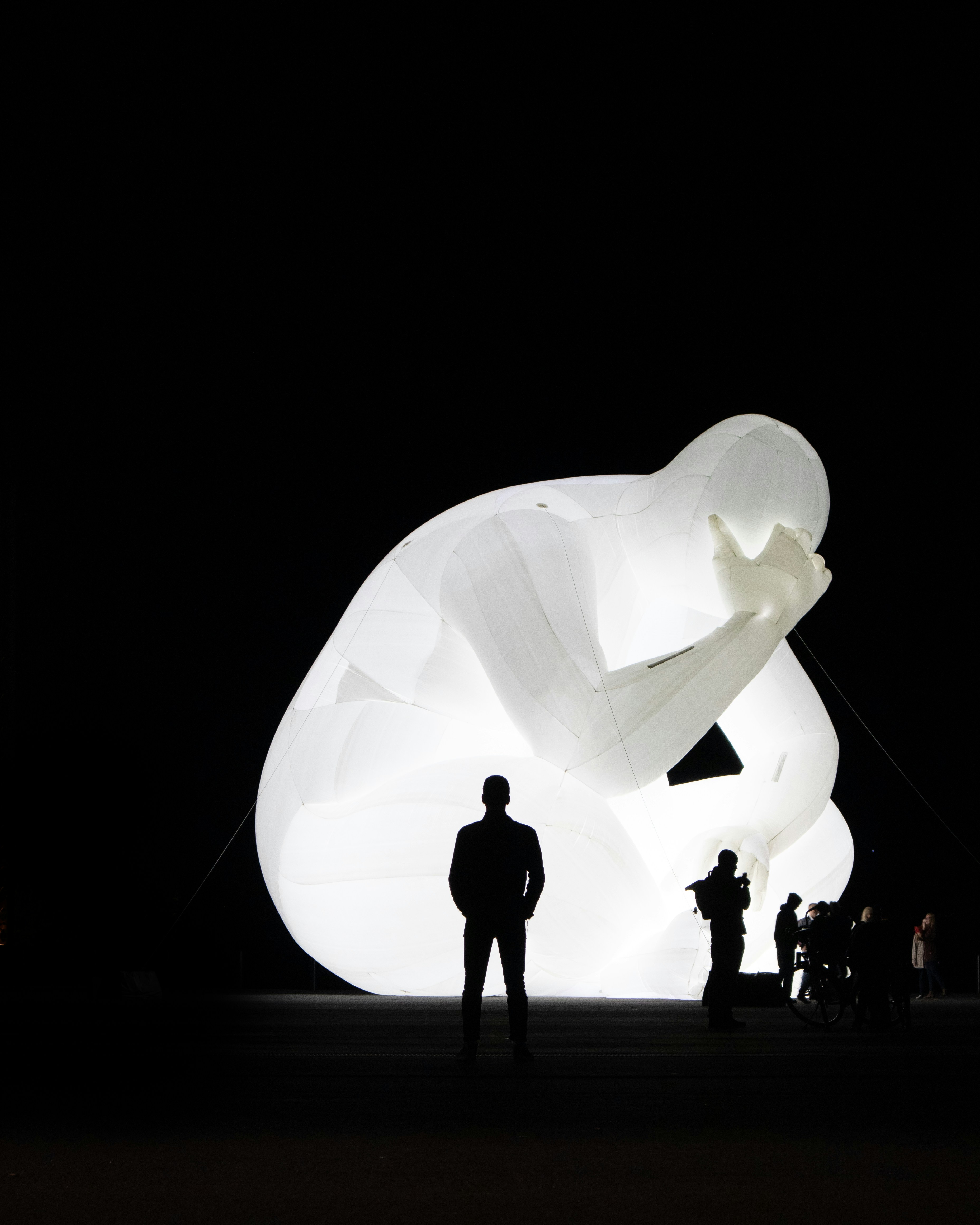 silhouette di persone in piedi accanto alla statua illuminata