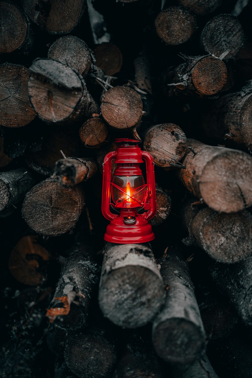 lampada lanterna rossa su legna da ardere accatastata