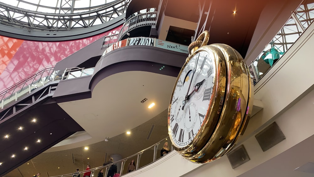 round brass-colored and white analog clock on wall