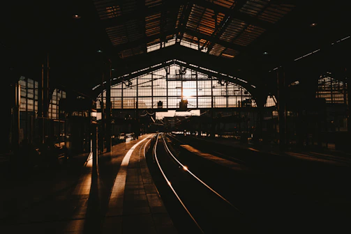 A rain-speckled window overlooking a dimly lit train station at twilight