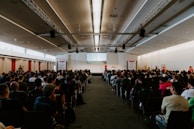 An inspiring speaker addressing an attentive audience at a modern event space with dark blue and white decor.