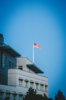 A sleek modern office building with the American flag waving outside, symbolizing government and policy work.