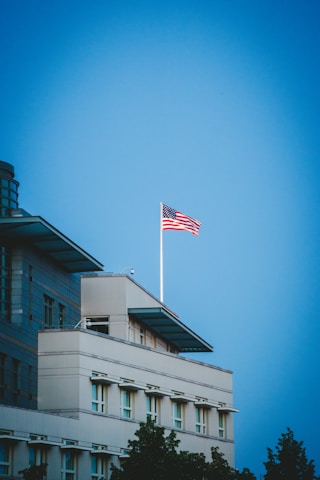 Modern corporate office building with American flag waving in front under a clear blue sky.