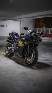 A sleek black and gold motorcycle helmet resting on a polished garage floor, bathed in warm light.