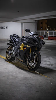 A sleek black and gold motorcycle helmet resting on a polished garage floor, bathed in warm light.