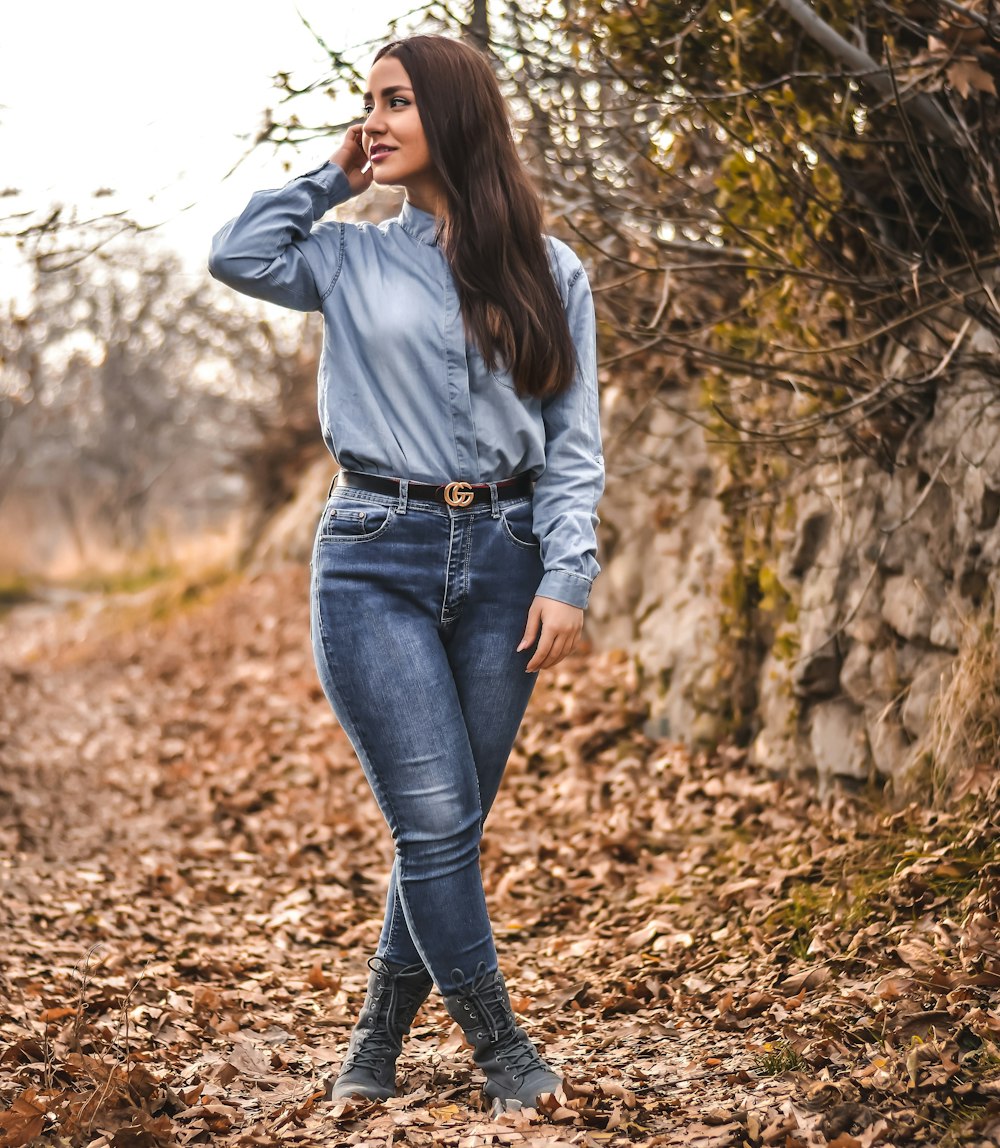 standing woman wearing gray dress shirt and blue denim jeans