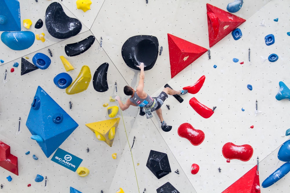 man wearing gray tank top climbing on wall