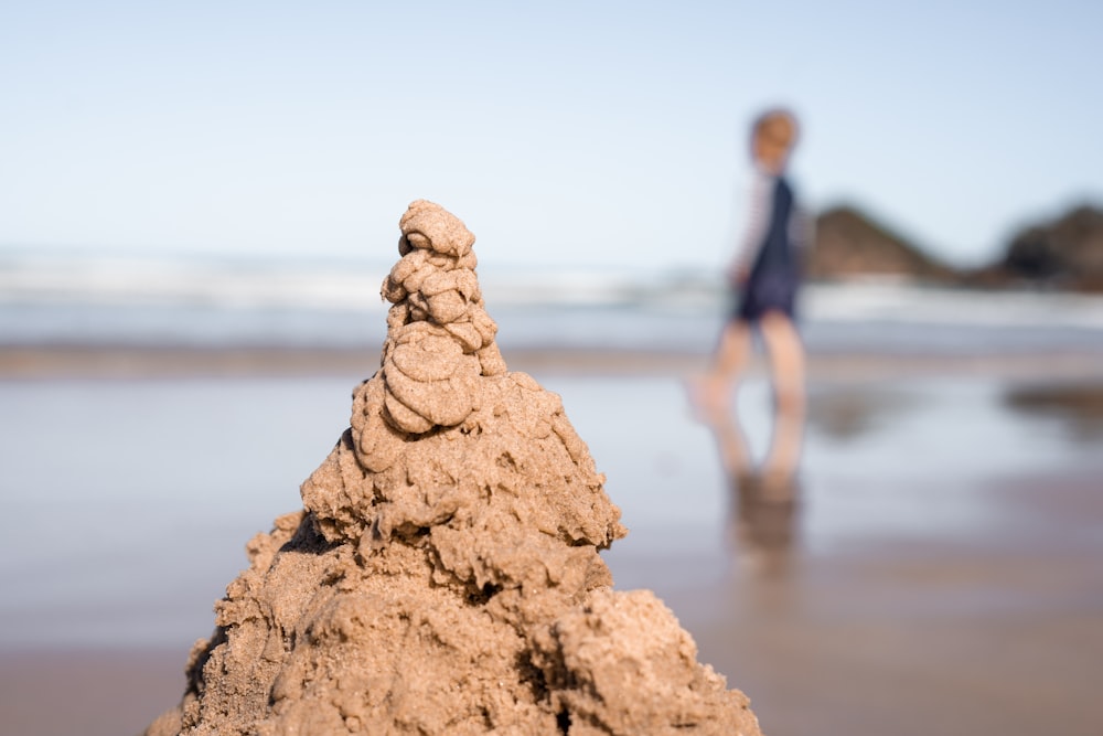 a sand castle on a beach with a woman in the background