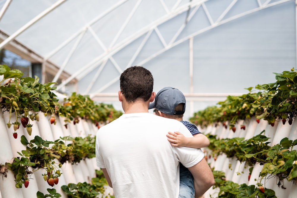 man carrying boy in green house