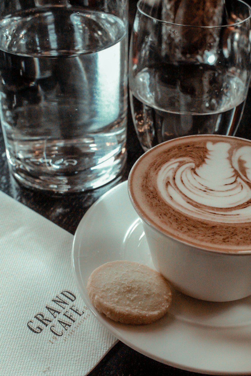 cup of latte and biscuit on saucer