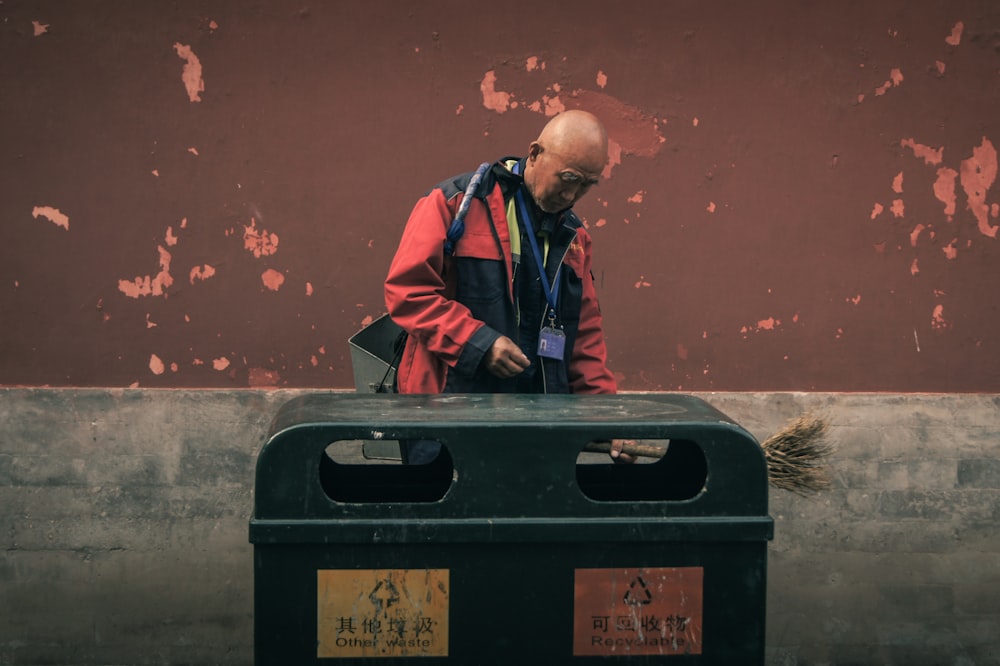 man standing beside trash biin