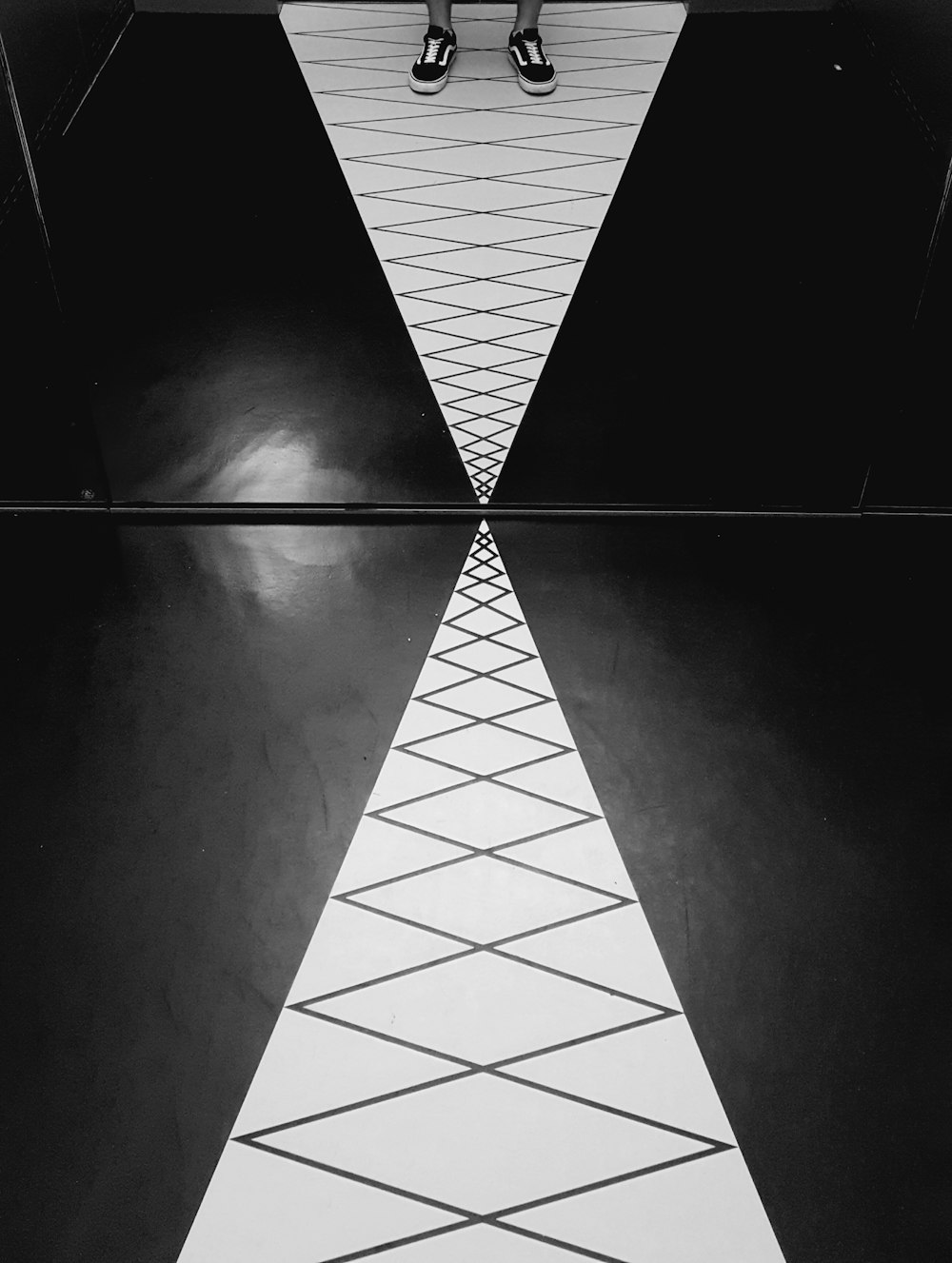 a black and white photo of a person standing on a tiled floor