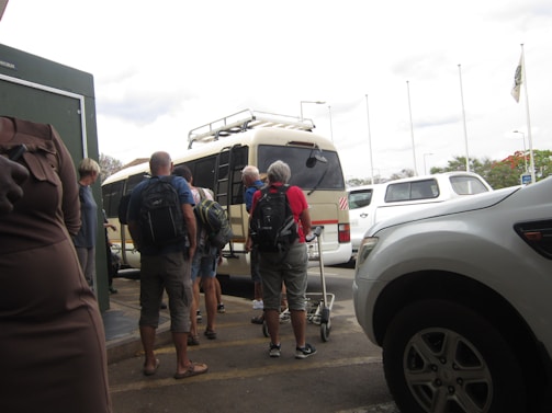 A friendly driver helping tourists with luggage beside a spacious minibus.