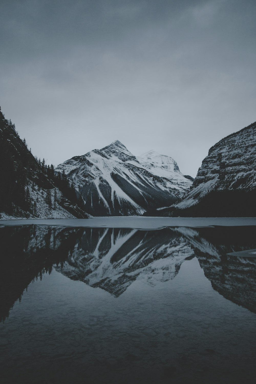 montanhas de neve e lago undr céu cinza