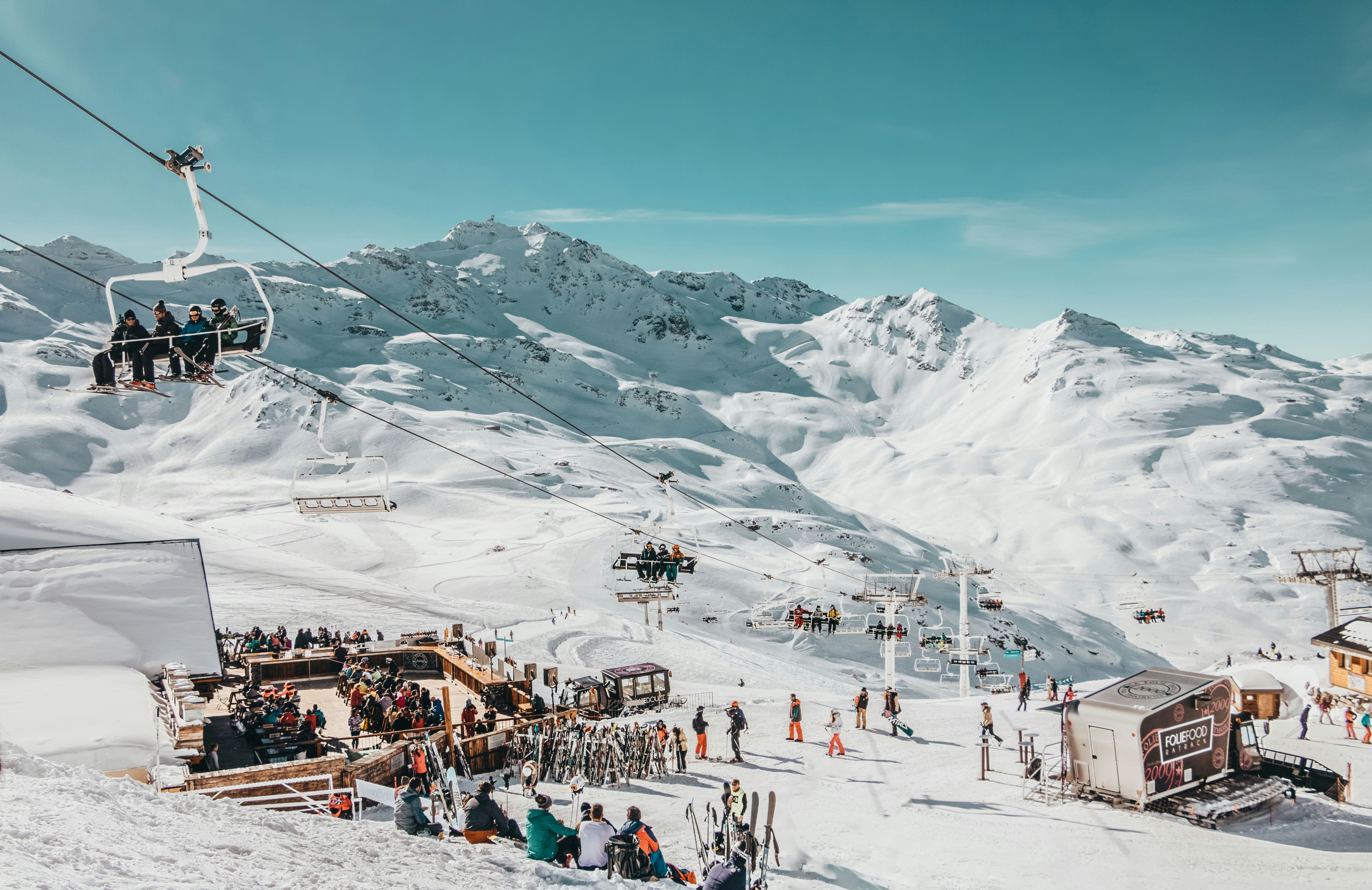 people riding on cable car above people on the ground with snow, La Folie Douce