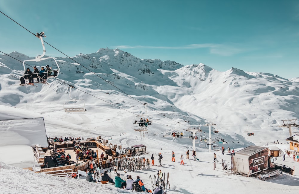 people riding on cable car above people on the ground with snow