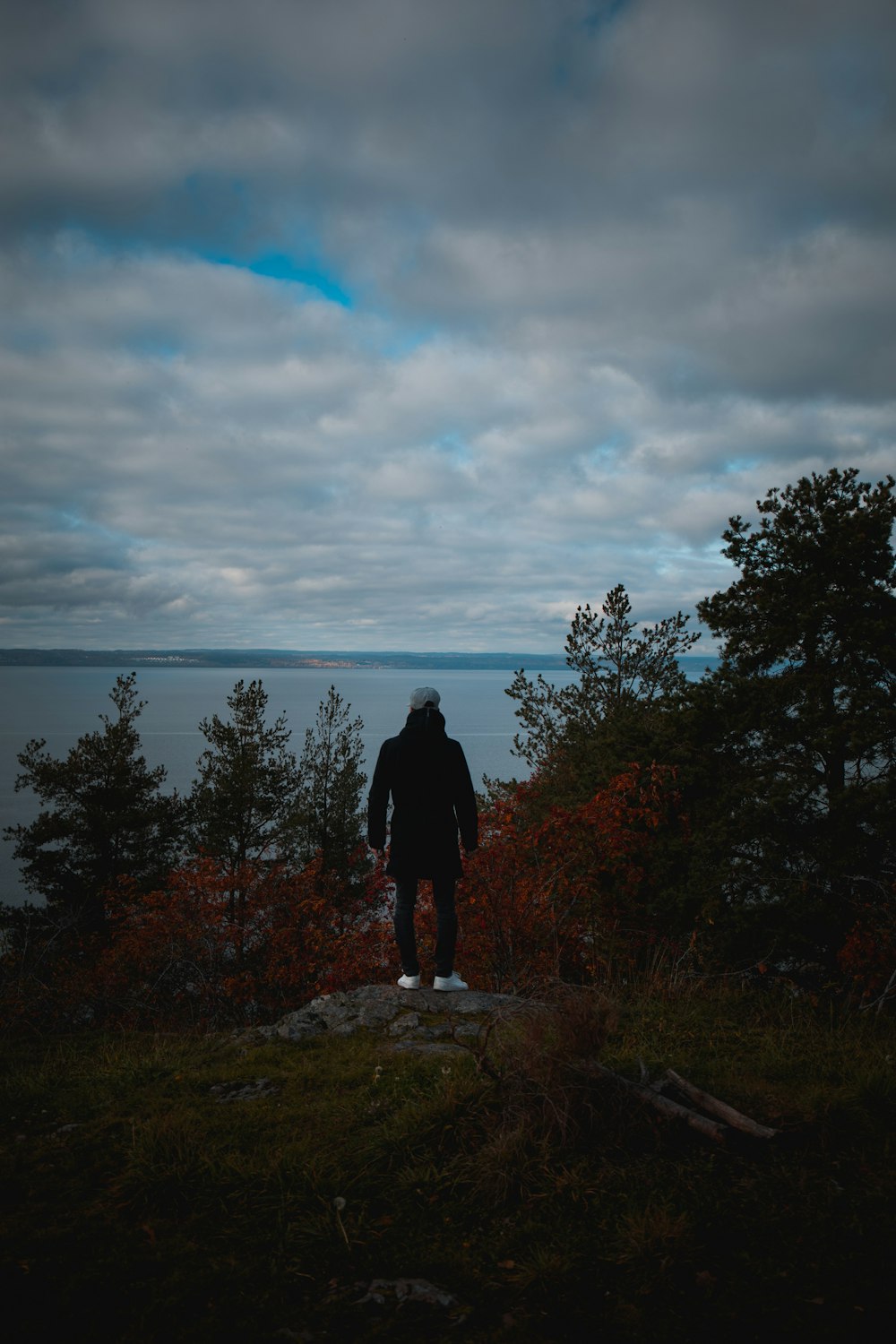 man standing on cliff facing sea