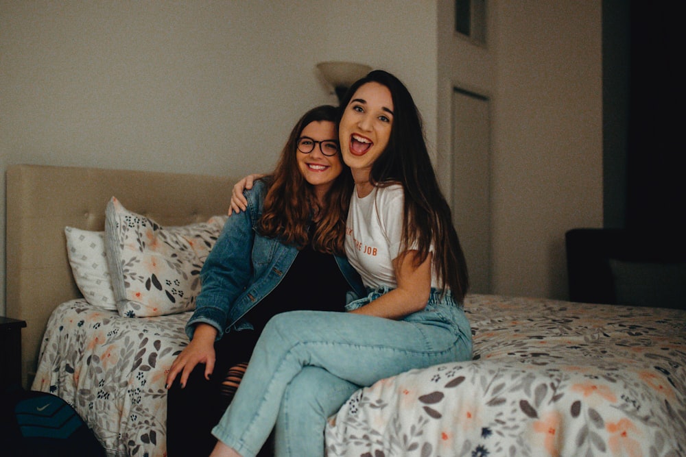 two women smiling while sitting on bed