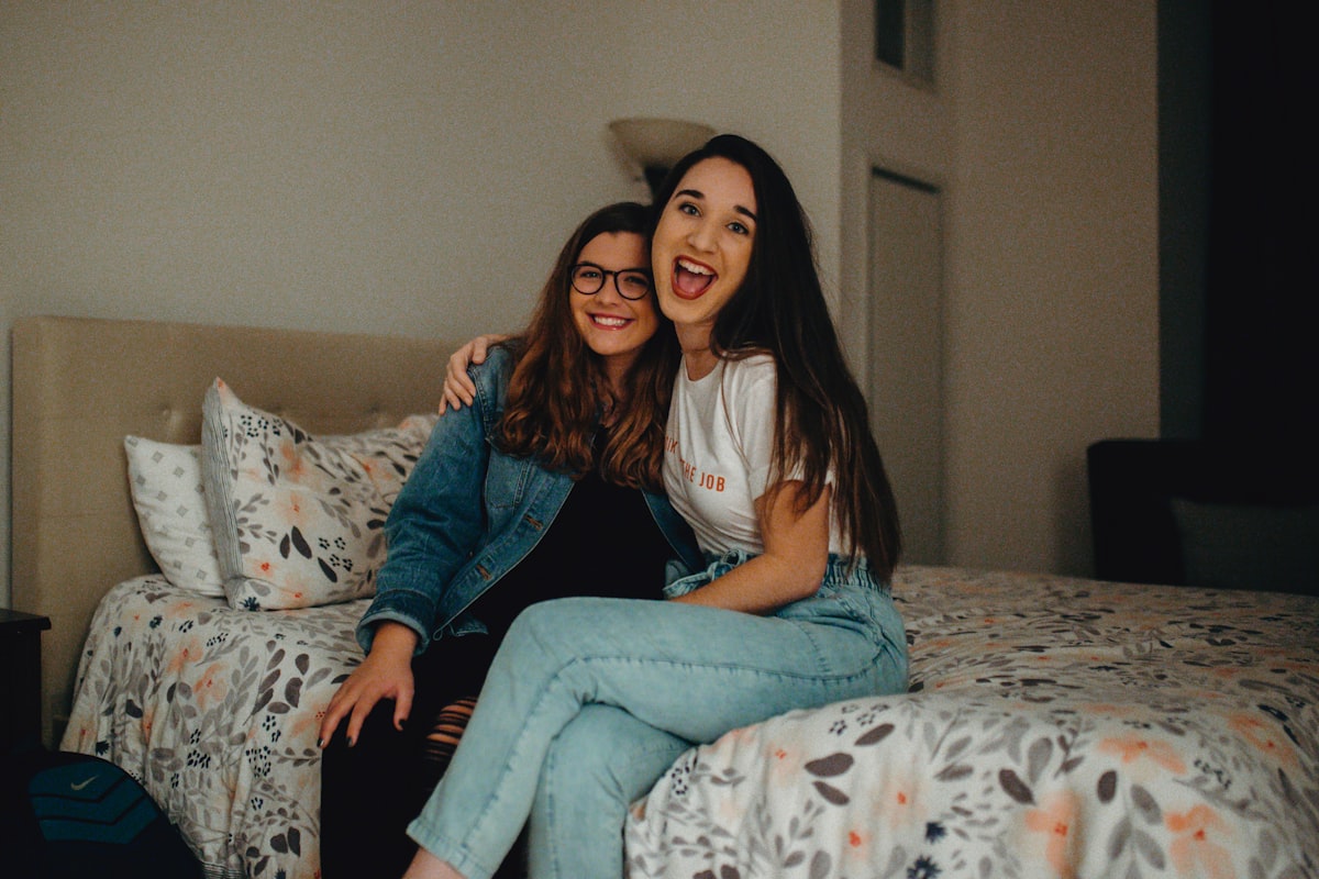 Two people smiling on a bed, overnight guests in a room