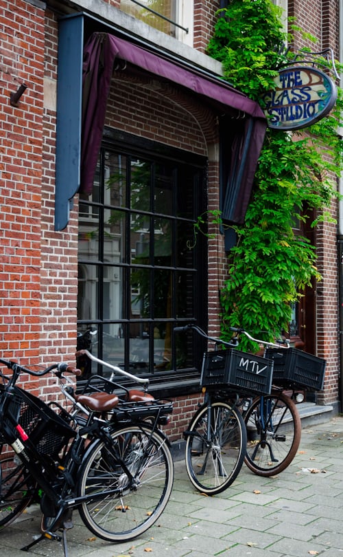 Bicycles parked on a bridge over a scenic canal in Amsterdam at sunset