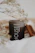 A softly glowing beeswax candle nestled among dried lavender and dark velvet fabric.