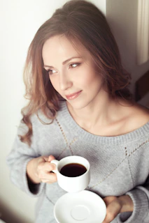 A peaceful image of a woman looking relieved and hopeful while holding a cup of tea in a quiet waiting area.