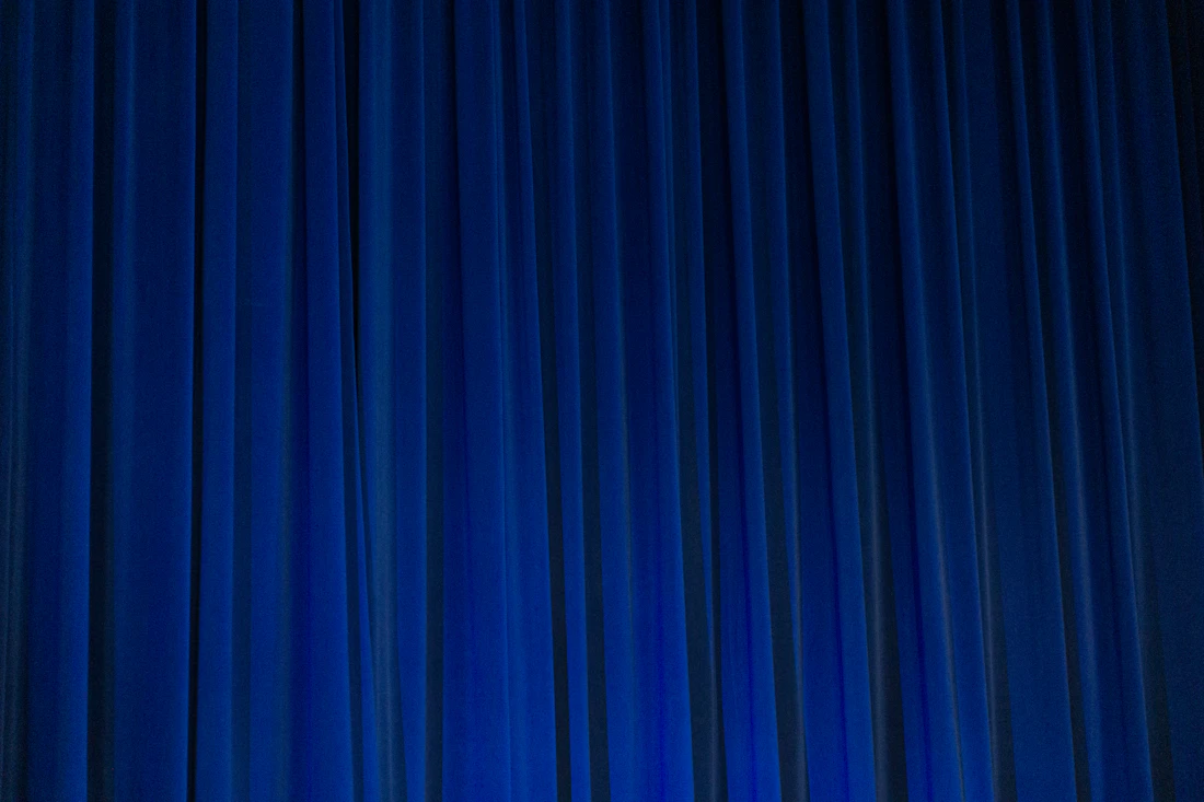 Man in a suit and tie in front of a blue curtain